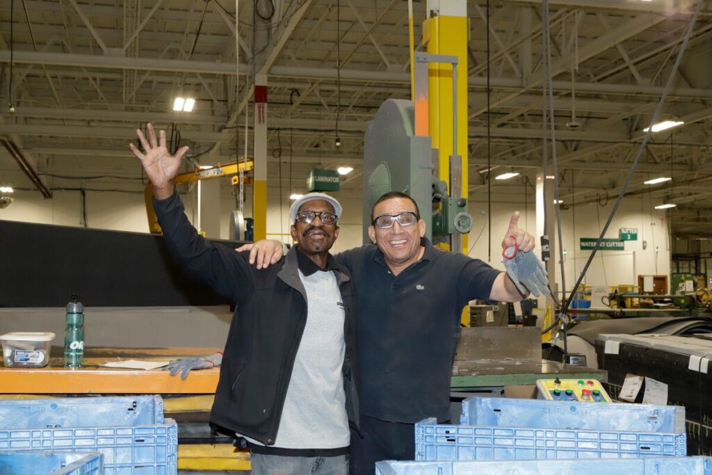 Two men waving at camera in warehouse