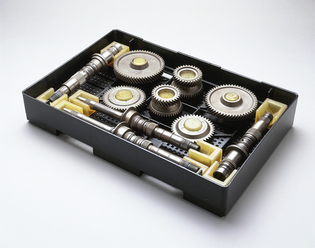 An injection molded kitting tray holds an assortment of metal gears and shafts, all neatly arranged for easy access.